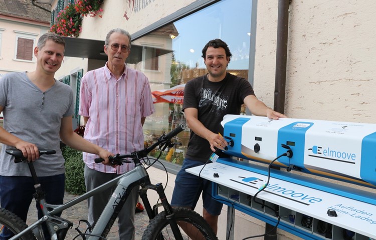 Vier E-Bikes können gleichzeitig geladen werden. V.l.: Erwin Moser von der Firma Elmoove brachte das Gerät, der Gemeinderat, vertreten durch Peter Müller, unterstützt das Projekt von Nils Gnädinger.