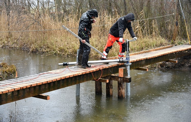 Arbeiter schrauben die Stahlpfosten für den Steg ins Wasser, nachdem die alte Brücke zur Hälfte entfernt wurde.