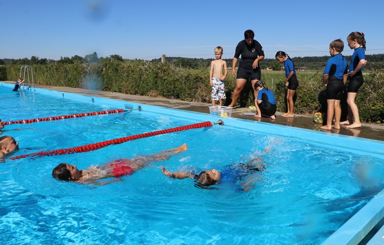 Rückenkraulen: Etwas, das die Kinder im Laufe der Intensivschwimmkurs-Woche von Schwimmlehrerin Yvonne Schmid (im schwarzen Neopren) gelernt haben.