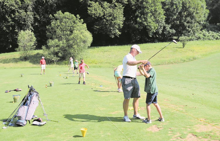 Golflehrer Paul Dougan zeigt einem Jungen die richtige Technik.