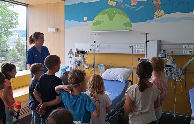 Pflegefachfrau Christa Boulos zeigt den Schülerinnen und Schülern ein Zimmer auf der Kinderstation und erklärt, welche Geräte es hier gibt.