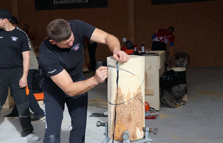 Der US-Amerikaner Jason Lentz bereitet sein Holzstück auf die Disziplin Standing Block Chop vor und zeichnet ein, wo er es später mit der Axt treffen will.