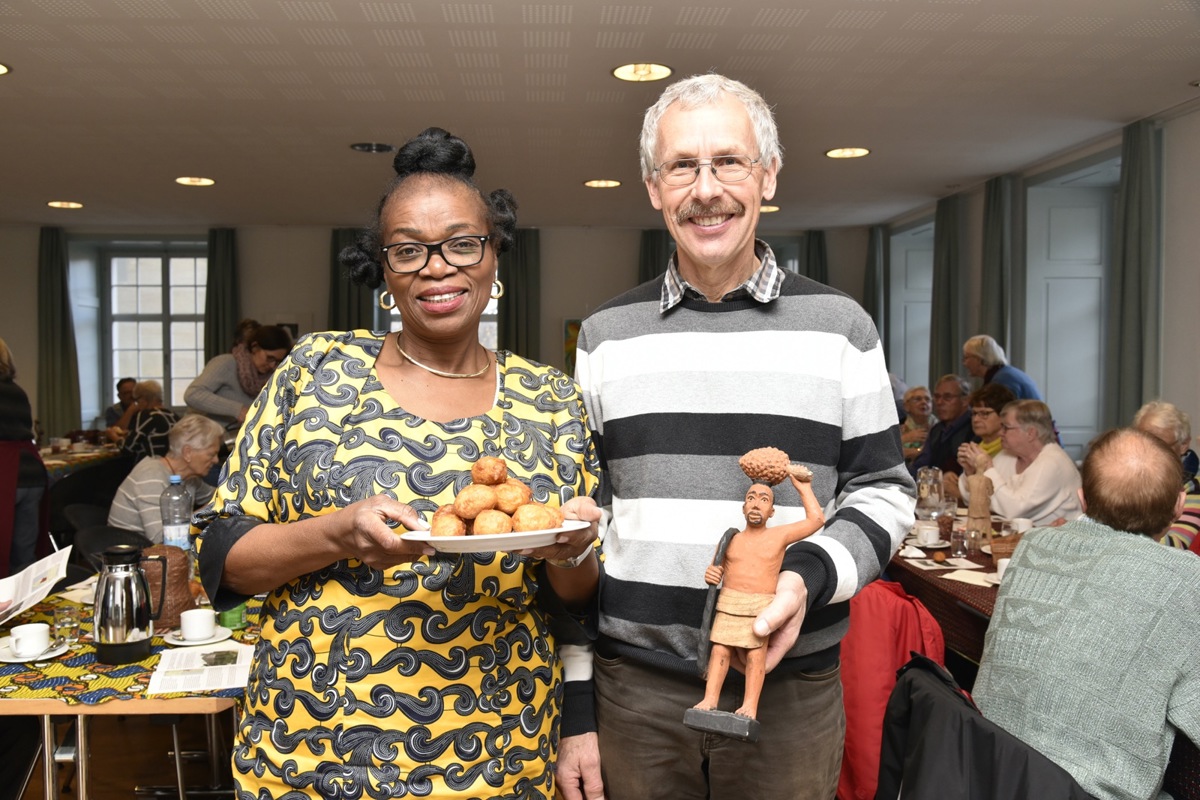 Jeannette Malonda Egg-Kuelo mit den frittierten Bällchen und Urs Weilenmann mit der geschnitzten Figur eines Palmöl-Ernters. Mit dem Band sichert er sich am Baum