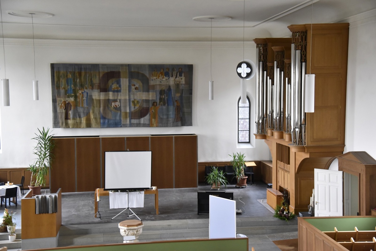 Der Chor der Kirche präsentiert sich heute mit Wandteppich und Orgel (rechts) hell und freundlich.