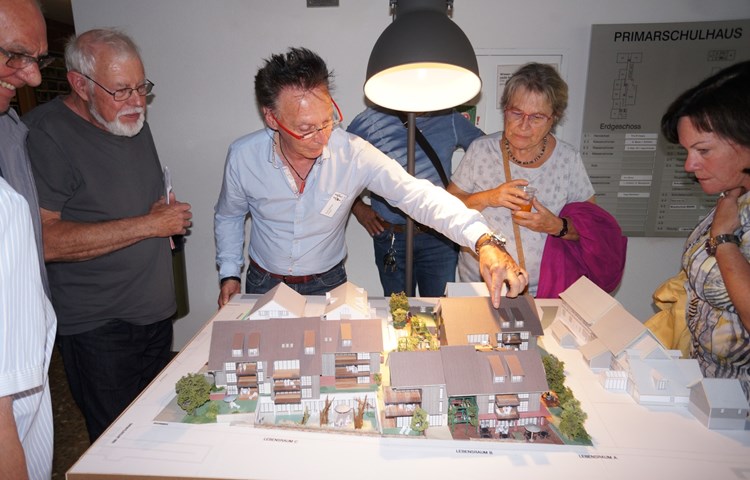 Projektverfasser Kurt Steiner (rote Brille, vor dem Gemeindehaus stehend) hat ein Modell im Massstab 1:100 gebaut. «Sagenhaft» lauteten die Kommentare von begeisterten Genossenschaftern. Das UG erhält Licht durch den vertieften Innenhof (im Bild vorne, Haus links).