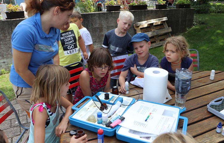 Betriebsleiterin Franziska König untersucht mit Kindern des Ferienprogramms Wasserproben aus den Innen- und Aussenbecken.