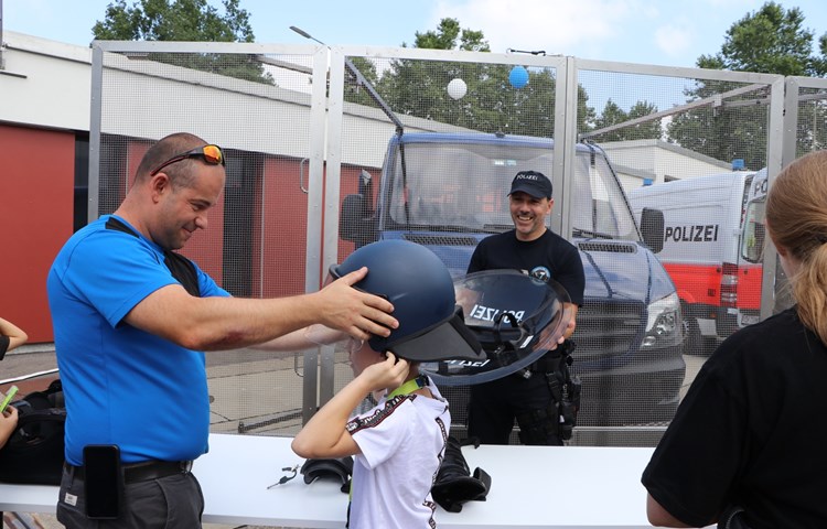 Ein Junge probiert die Schutzausrüstung an, welche die Polizisten beispielsweise bei Demonstrationen tragen.
