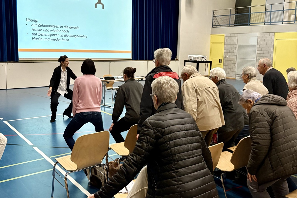 Friederike Schulte, Mitbegründerin des Sturzzentrums Schweiz und das Publikum absolvierten drei Übungen, die das Sturzrisiko minimieren können. Der Zweibein-Zehenstand trainiert die Muskeln im Oberschenkel. 