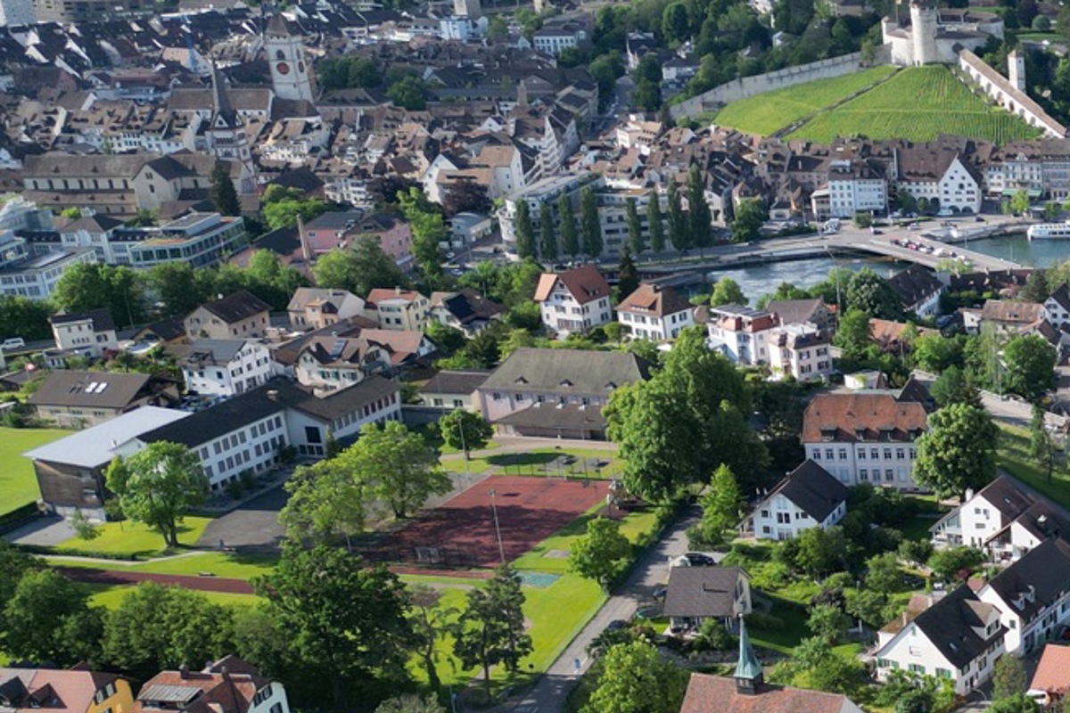 Die halb eingegrabene Doppelhalle soll rechts in die bestehende Schulanlage integriert werden.