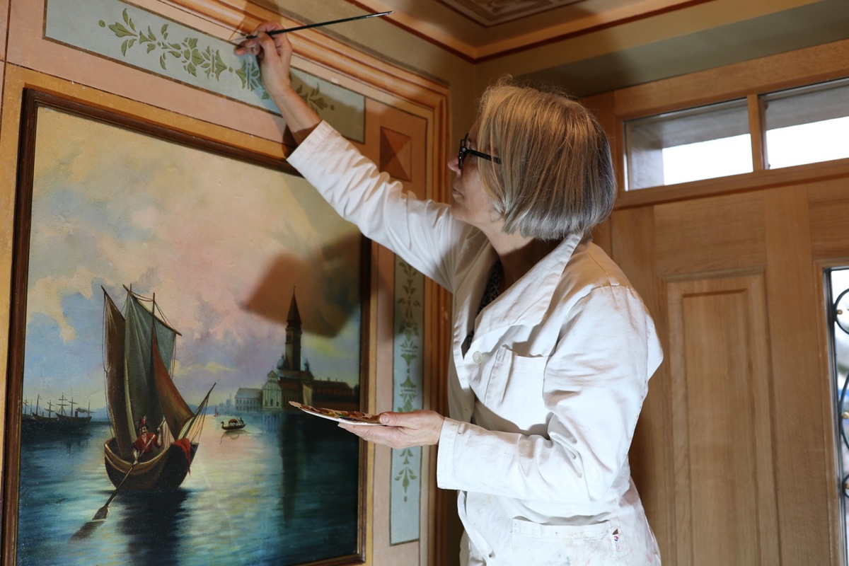 Anita Wanner restauriert die Wandmalerei im Gang der Friedau