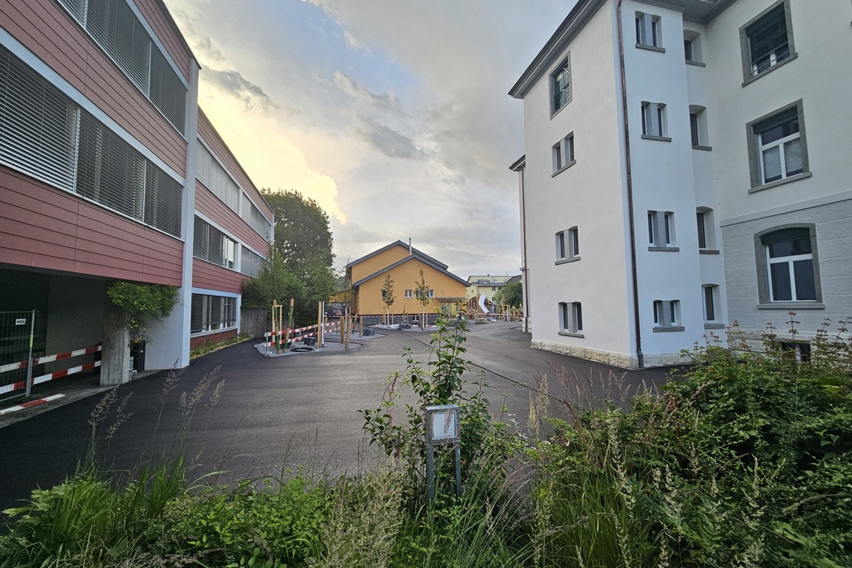 Die letzten Arbeiten laufen: Pünktlich zu den Sommerferien sind der sanierte Pausenplatz sowie der neue Spielplatz (im hinteren Teil) fertiggestellt.