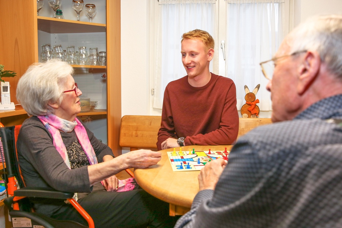 Aktivierung ist ein wichtiger Bestandteil der professionellen Betreuung. Hier macht der Lernende Lars Gächter ein Gesellschaftsspiel mit zwei Tagesgästen.
