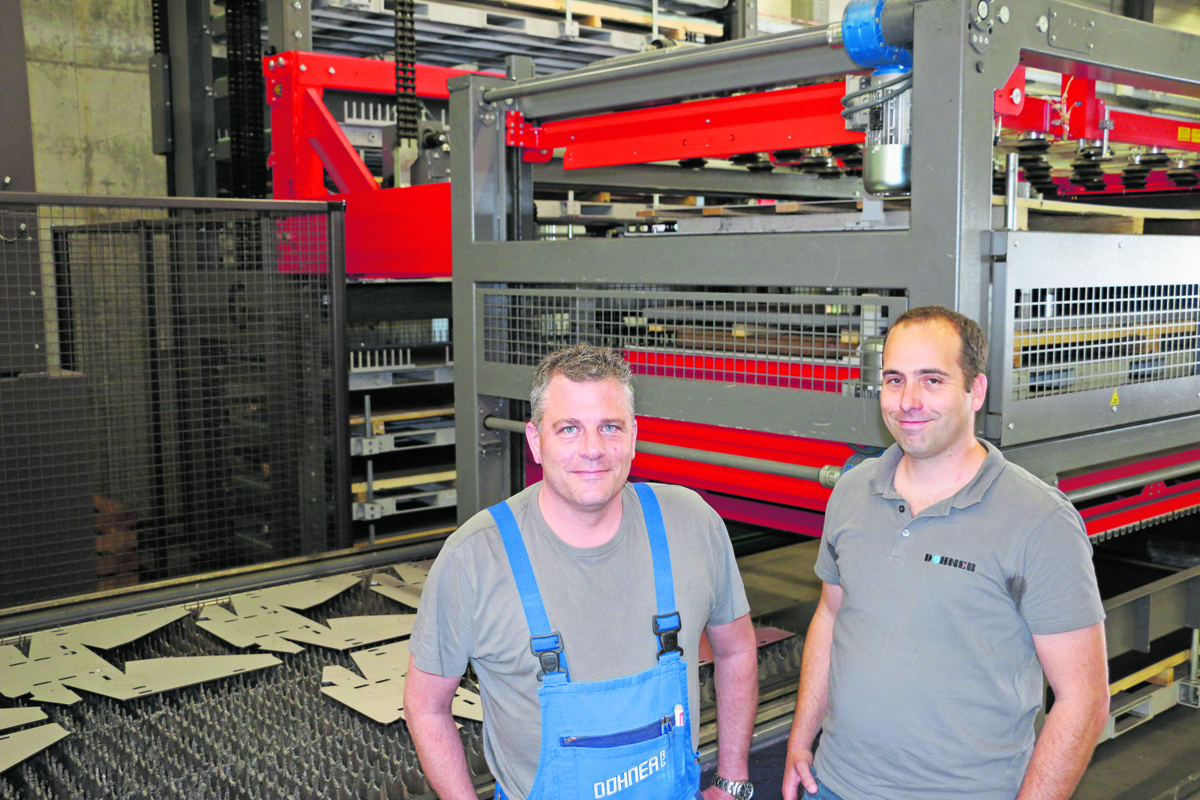 Andreas Sauter und Lukas Riedo (rechts) vor der Faserlaseranlage mit automatischem Blechlager.