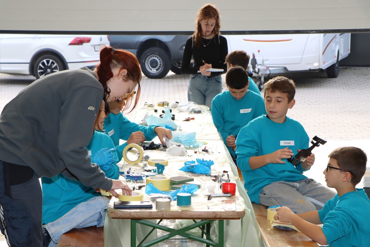 Konzentriert bei der Arbeit am Zukunftstag: Die Gäste der Gehrig Carrosserie am Tisch, die AZ-Reporterin im Hintergrund.