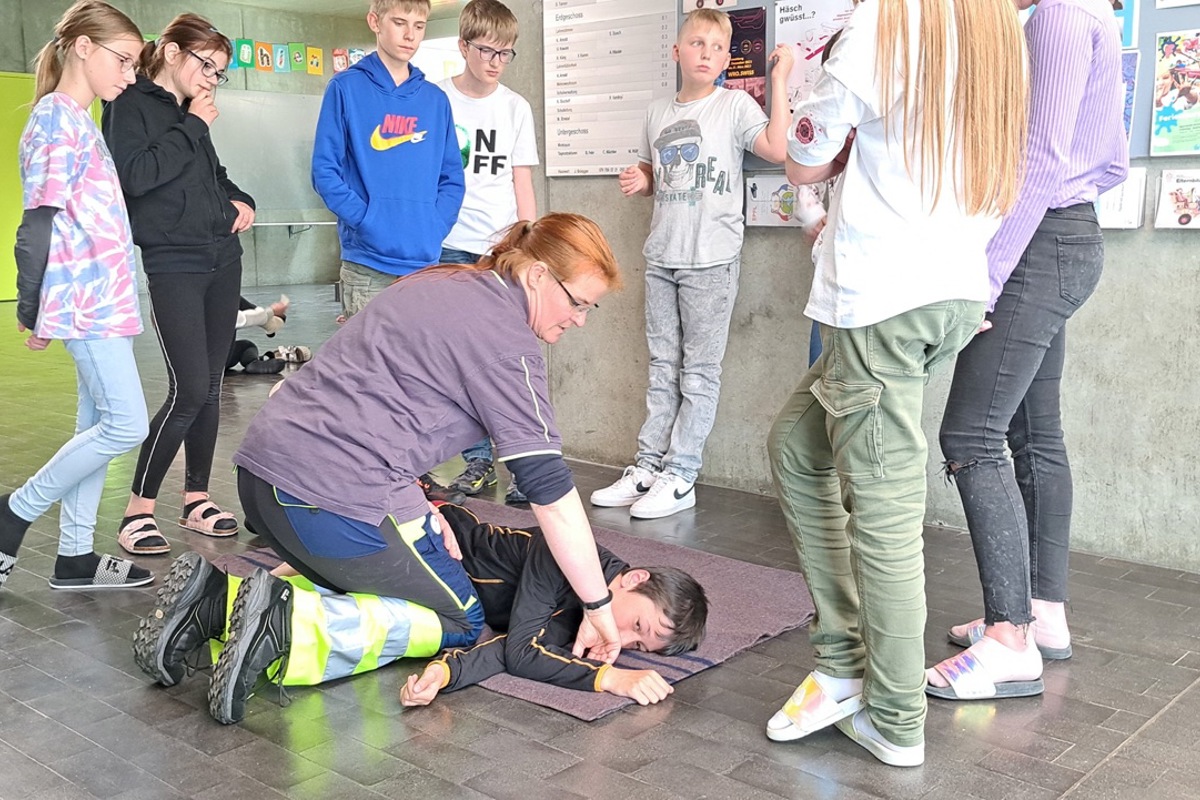 Samariterin Heidi Strasser führt den Jugendlichen die stabile Seitenlage bei Bewusstlosigkeit vor.