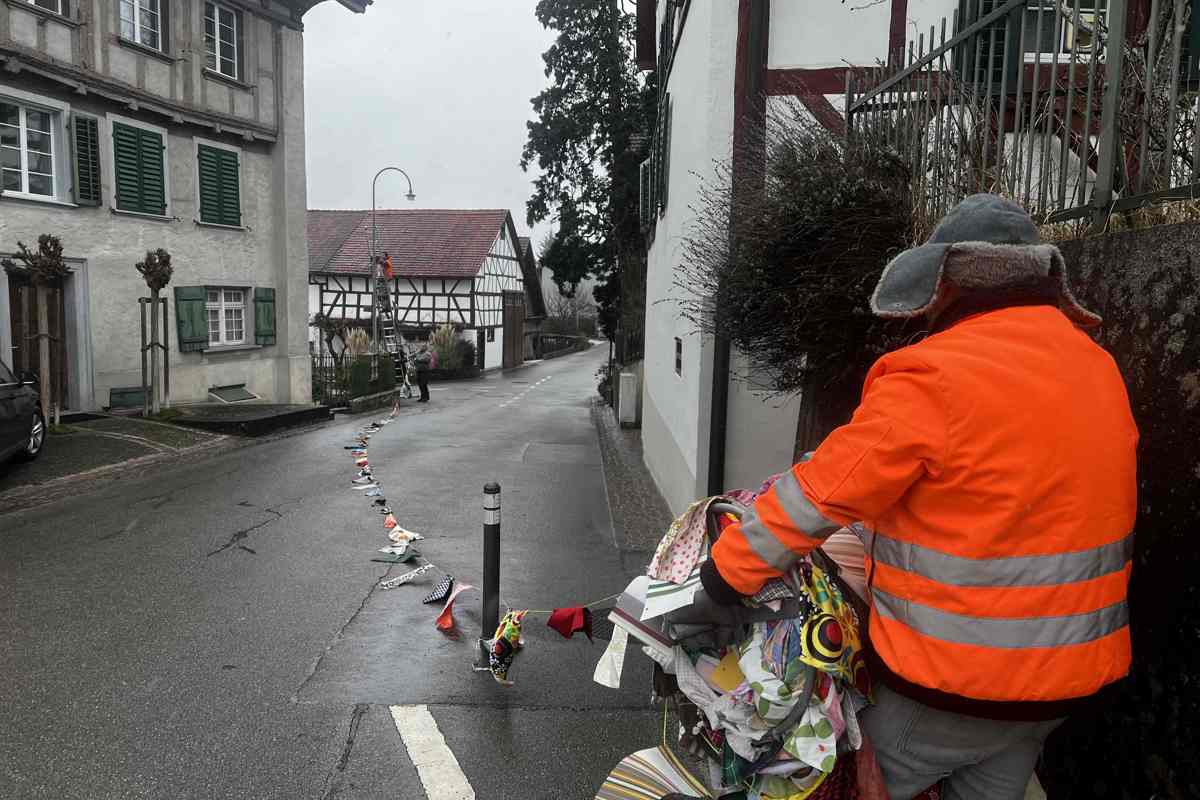 Alain Bieler hält die Rolle mit der frisch gewaschenen Girlande, während Marcel Kern auf die Leiter steigt und die Girlande sicher an den Häusern befestigt.