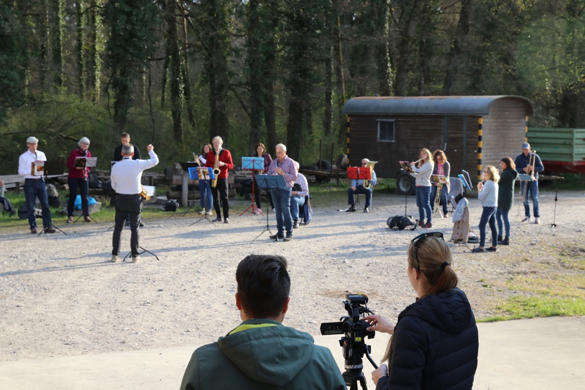 Die Bläserklasse unter der Leitung von Marco Weber übt Corona-konform im Freien – David Stäheli und eine Video-Journalistin sind auch da.