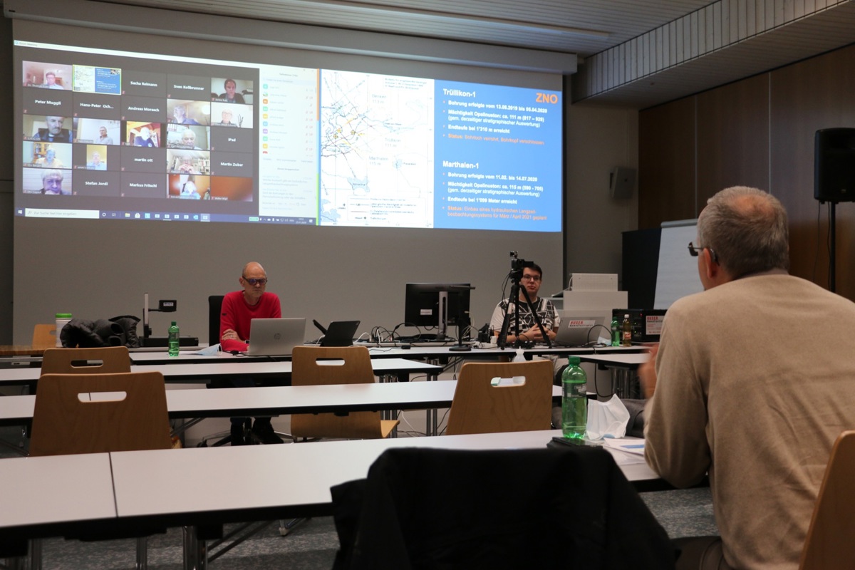 Für einmal reichte der kleine Saal des AZA: Nagra-Geologe Philip Birkhäuser (brauner Pulli) erklärt den von zu Hause eingeloggten Konferenzmitgliedern (zu sehen auf der linken Hälfte der Leinwand) den Stand der Tiefbohrungen. Für einmal reichte der kleine Saal des AZA: Nagra-Geologe Philip Birkhäuser (brauner Pulli) erklärt den von zu Hause eingeloggten Konferenzmitgliedern (zu sehen auf der linken Hälfte der Leinwand) den Stand der Tiefbohrungen.